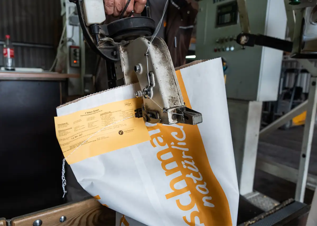 Ein Sack r’ leben senior Pferdefutter wird mit einer Maschine verschlossen